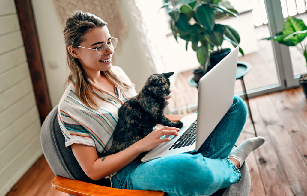 CatTalk Onlineberatung Frau sitzt auf Stuhl mit Laptop und Katze auf dem Schoß